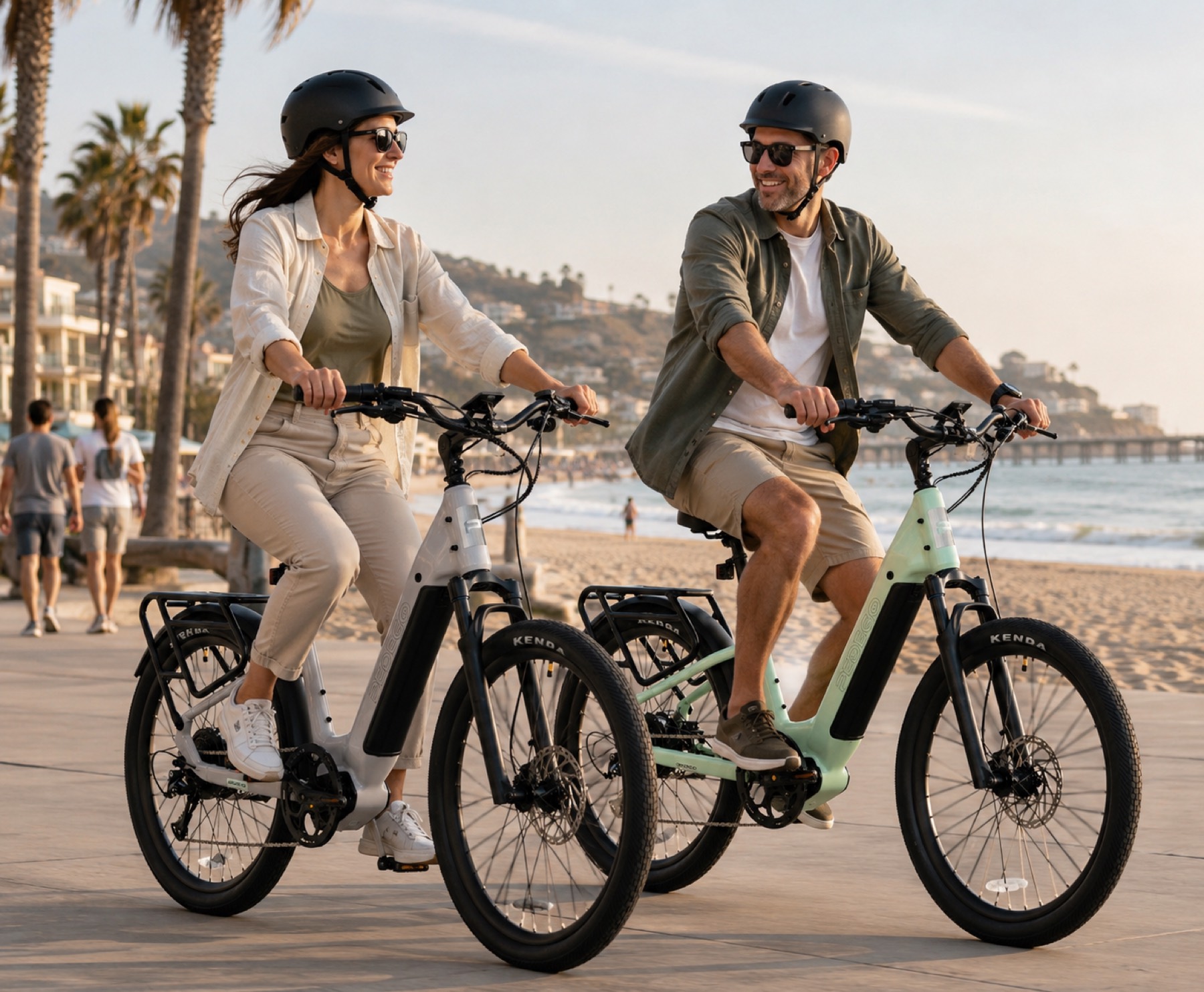 Two riders on Pedego e-bikes on a palm-lined beachfront path