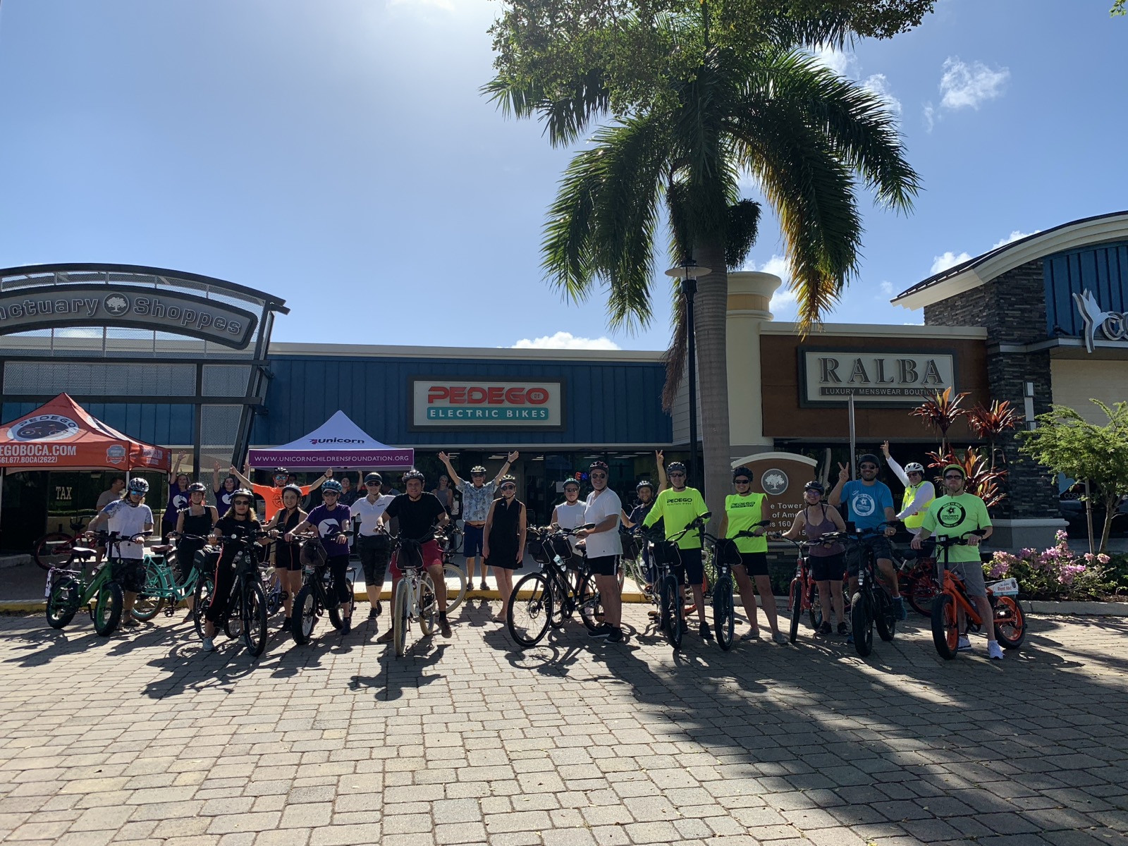 More than twenty riders with their bikes outside the shop before a charity ride for the Unicorn Children's Foundation