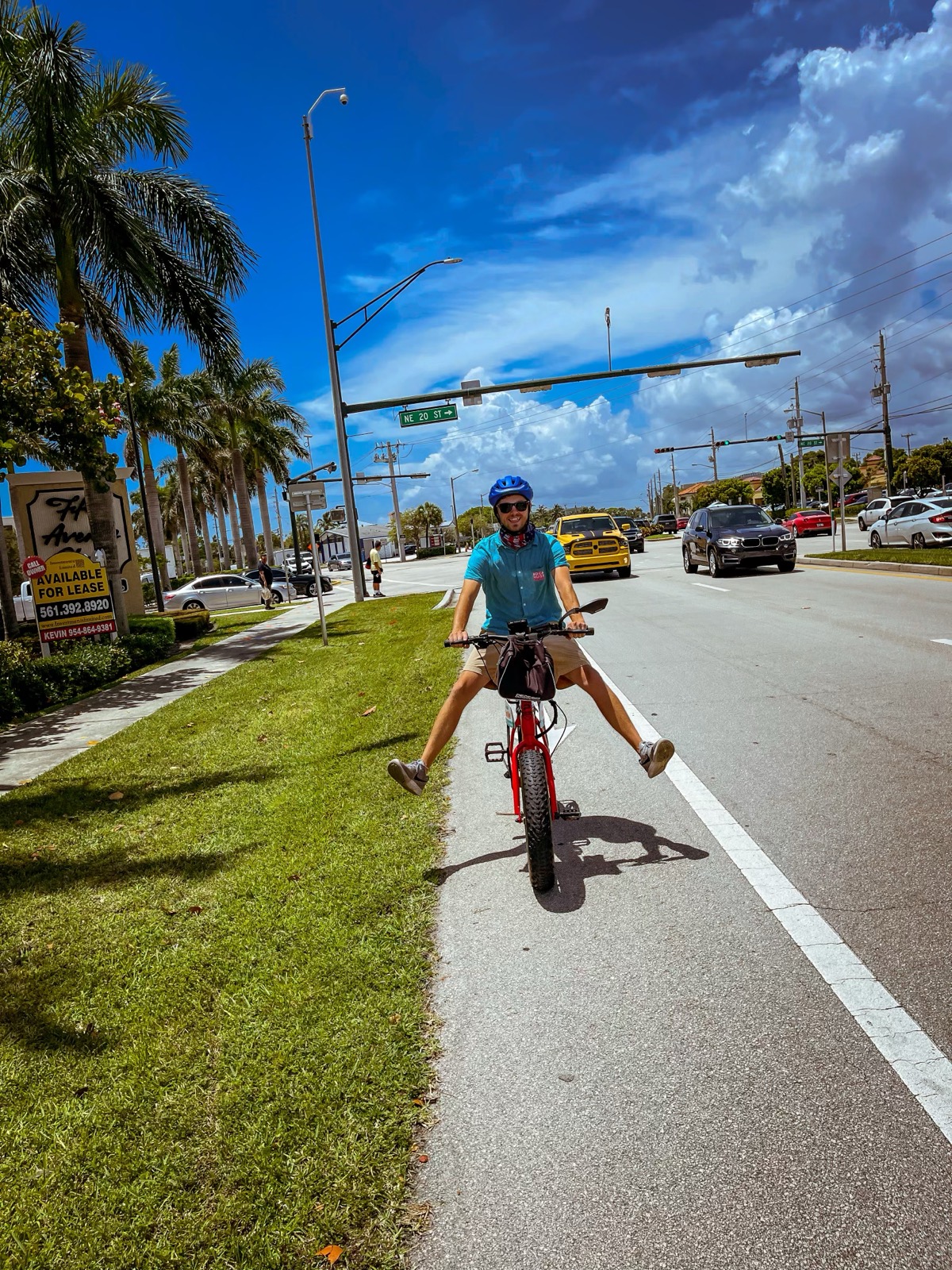 Kyle riding a red fat-tire electric bike along a palm-lined road in Boca Raton